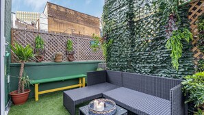 A patio with a wicker sofa, a bench, and potted plants. - Charming 2bed Garden Apartment in Covent Garden (London)