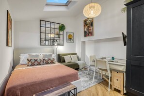 Quarto moderno com cama, escrivaninha e claraboia.