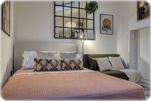 Quarto com cama, mesas de cabeceira, janela e decoração nas paredes.