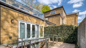 A brick building with a glass balcony, a metal railing, and a hedge. - Mahogany Heights in Greater London (London)