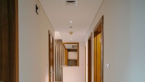 A narrow, well-lit hallway with a tiled floor, wooden doors, and a small step leading to a room. - Prime Downtown Dubai 2-bed 2-bath With Parking (Dubai)