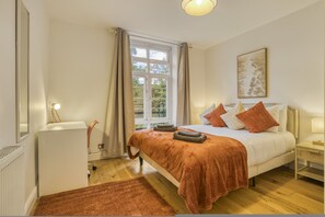 A bedroom with a bed, a window, a radiator, and a painting on the wall. - Comfortable 2-bed in Zone 2 (London)