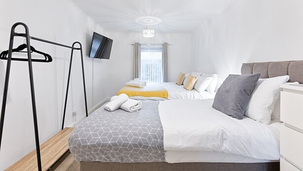 A hotel room with a bed, a TV, a wardrobe, and a window with curtains. - Group-Friendly Home | TV in Every Room, WiFi & Parking (Bon-y-maen)