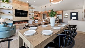 Une cuisine moderne avec une table à manger en bois pouvant accueillir six personnes, une cheminée et un téléviseur fixé au mur.