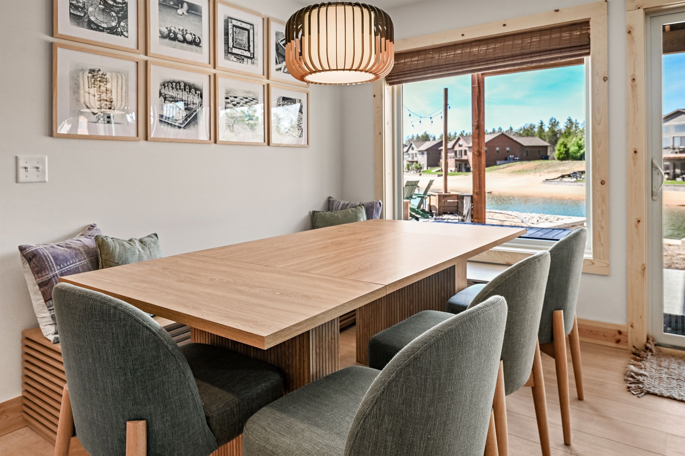 A dining area with a wooden table, grey upholstered chairs, and framed pictures on the wall.
