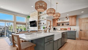 Une cuisine moderne dotée d’un grand îlot central, de meubles en bois et de luminaires suspendus.