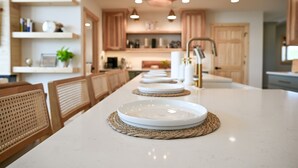 Une cuisine moderne avec un grand îlot central, des chaises en bois et des luminaires suspendus.