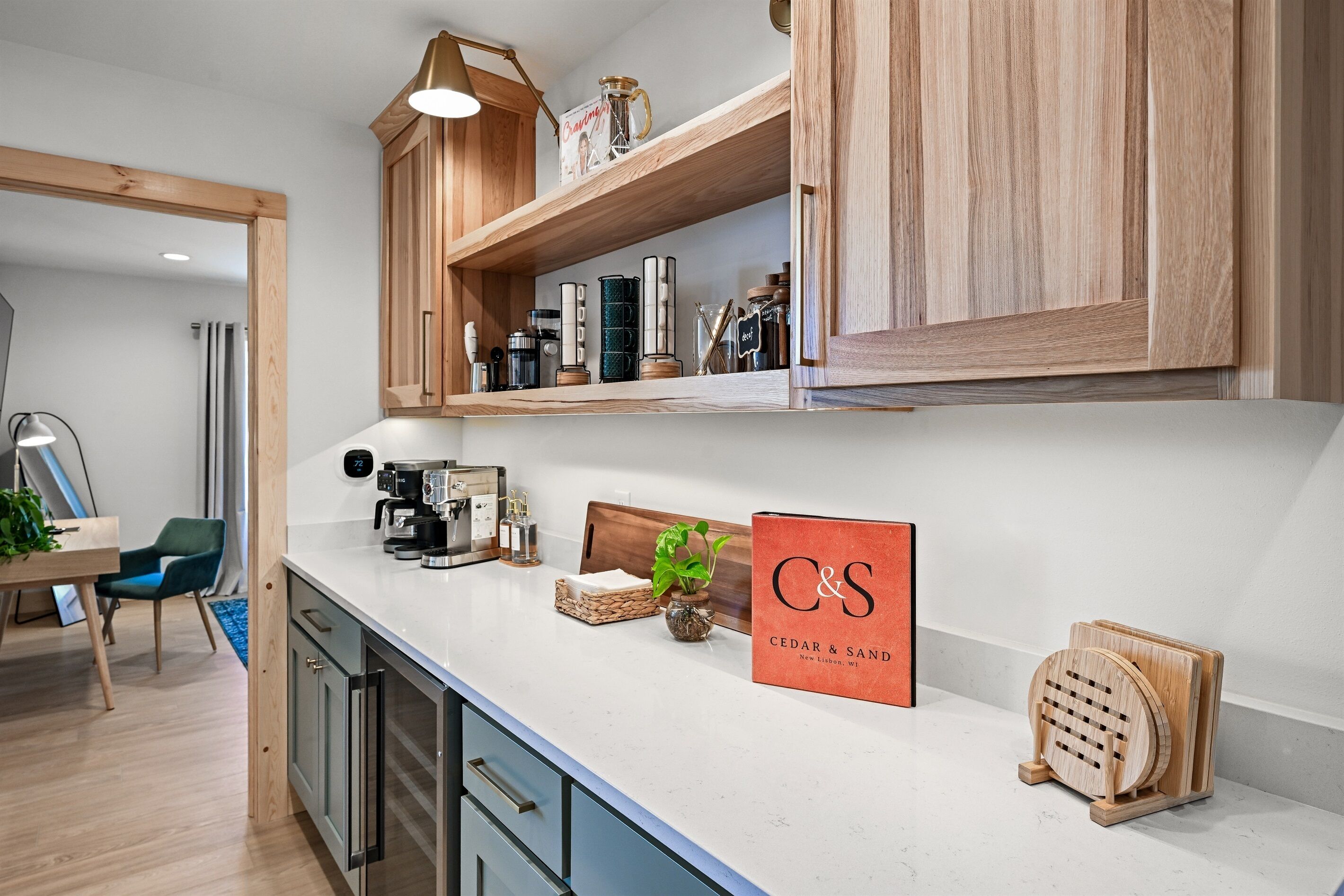 Una cocina moderna con armarios de madera, encimera blanca y diversos electrodomésticos.