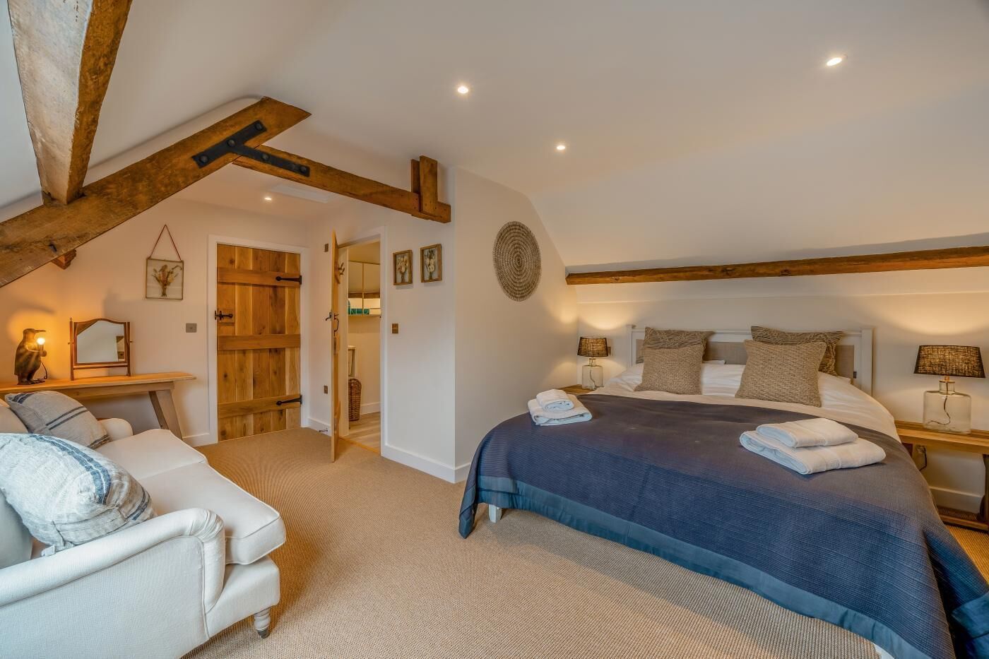 A bedroom with a large bed, bedside tables, a chair, and a wooden door.