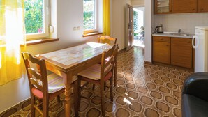 A dining area with a table and chairs, a kitchen with wooden cabinets, and a patterned floor. - Apartment created for enjoyment (Crikvenica)