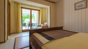 A hotel room with a bed, a view of the outside, and a chair by the window. - Apartment created for enjoyment (Crikvenica)