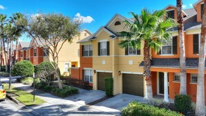 A row of two-story townhouses with attached garages, surrounded by palm trees and well-maintained lawns. - Mouse House 5 miles to Disney sleeps 9 (Kissimmee)