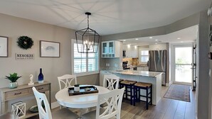 Een moderne keuken met een centraal eiland, witte kasten en een eethoek met een ronde tafel en stoelen.