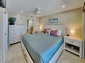 A bedroom with a bed, nightstands, a dresser, a ceiling fan, and a painting on the wall. - Pointe South 504 | Newly Reno, Stunning Gulf Views + Pool (Fort Myers Beach)