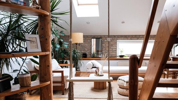 Una sala de estar acogedora con un columpio, estanterías de madera y una lámpara colgante.