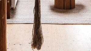 Una sala de estar moderna con una cuerda colgante, un sofá blanco, una mesa de centro de madera y una lámpara.