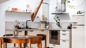 Una cocina moderna con una mesa de comedor de madera, armarios blancos y una campana extractora de acero inoxidable.