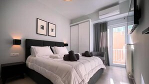 Een moderne hotelkamer met een groot bed, een flatscreen televisie, een wandlamp en een schuifdeur naar een balkon.