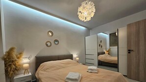 A modern bedroom with a large bed, bedside tables, a mirror, and a wardrobe. - Sagar Residential Apartment - Athens Town (Nea Ionia)
