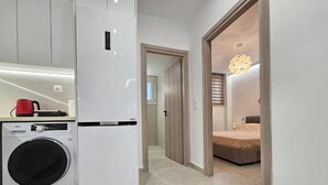 A modern apartment with a kitchen, a washing machine, a bed, and a hallway. - Sagar Residential Apartment - Athens Town (Nea Ionia)