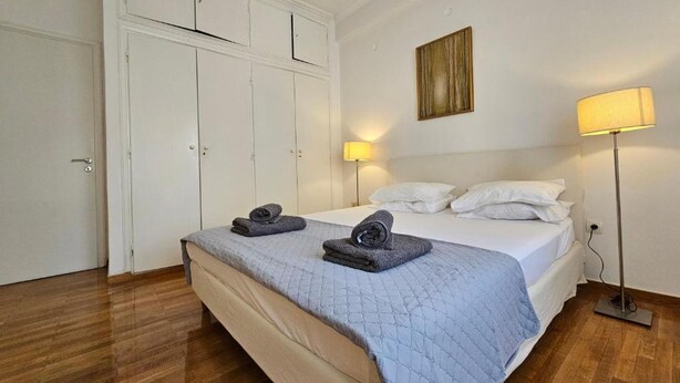 Une chambre d’hôtel avec un lit, deux lampes de chevet, un tableau au mur et une armoire.