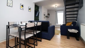 Uma sala de estar moderna com uma mesa de jantar, sofá azul e uma escada.