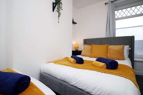 Une chambre d’hôtel avec un lit, une table de chevet, une lampe et une fenêtre avec des rideaux.