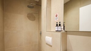 A bathroom with a shower, a toilet, and a sink. There is a sign prohibiting the disposal of trash in the toilet. - Grandstay Tirana Central 01 (Tiranë)