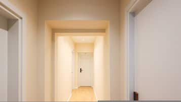A narrow hallway with a door at the end, leading to a room with a visible door handle.