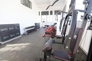 Ein Fitnessraum mit Trainingsgeräten, Gewichten und einer Bank.