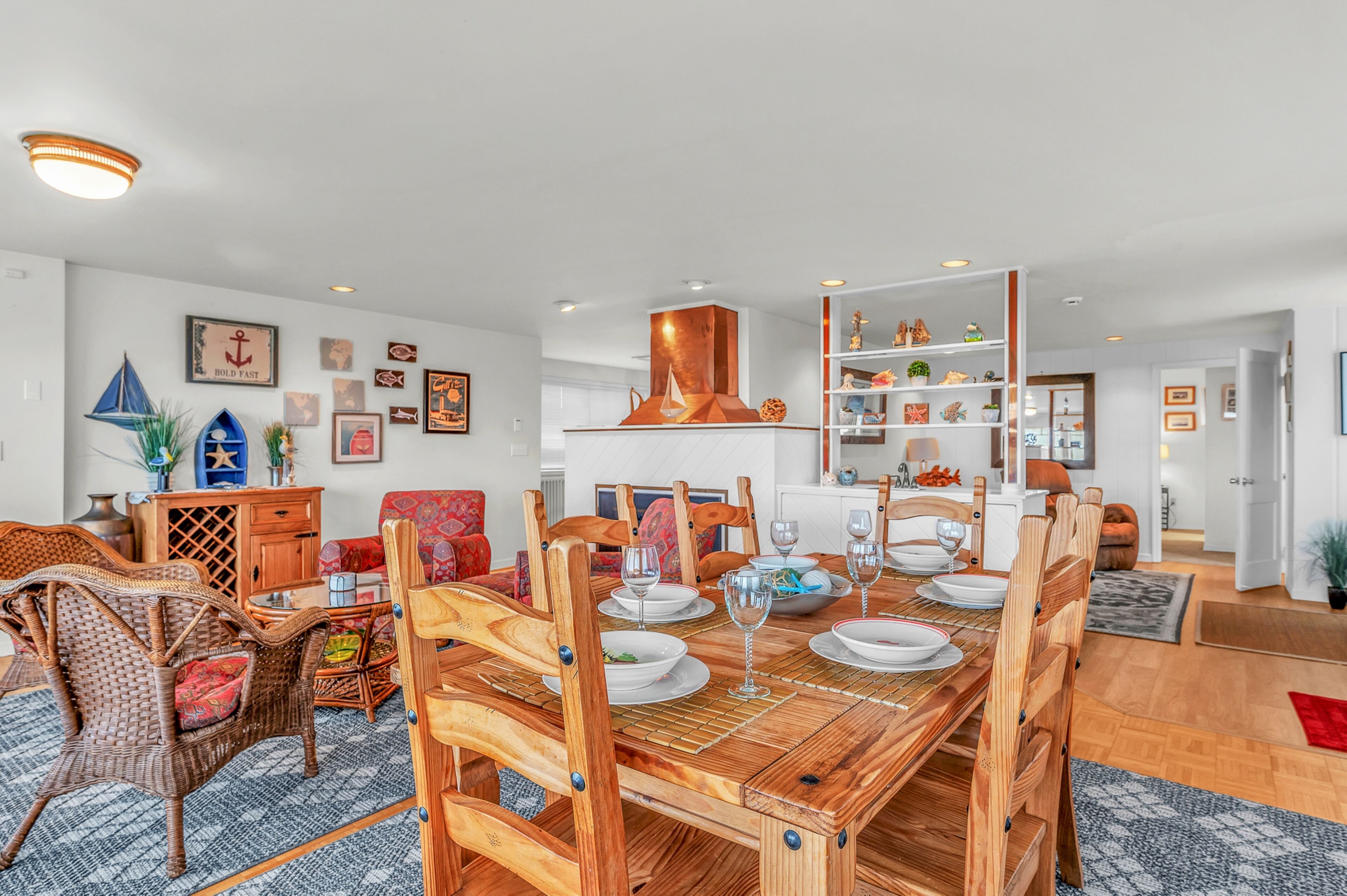 Comedor con mesa de madera dispuesta para cuatro personas, rodeado de sillas de mimbre.