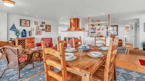 Un coin repas avec une table en bois dressée pour quatre personnes, entourée de chaises en osier.