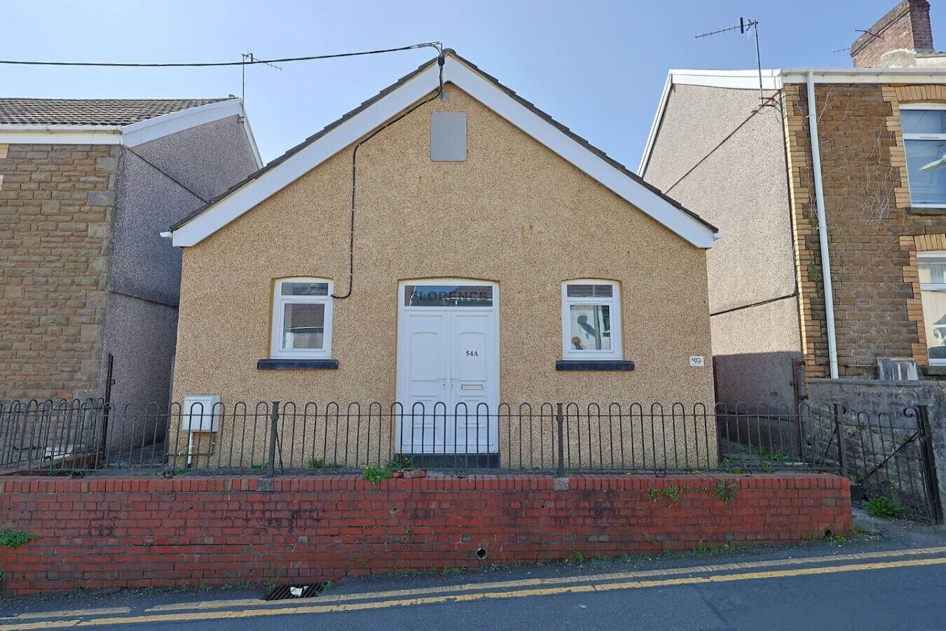 A two-story building with a white door, two windows, and a small overhang above the door.