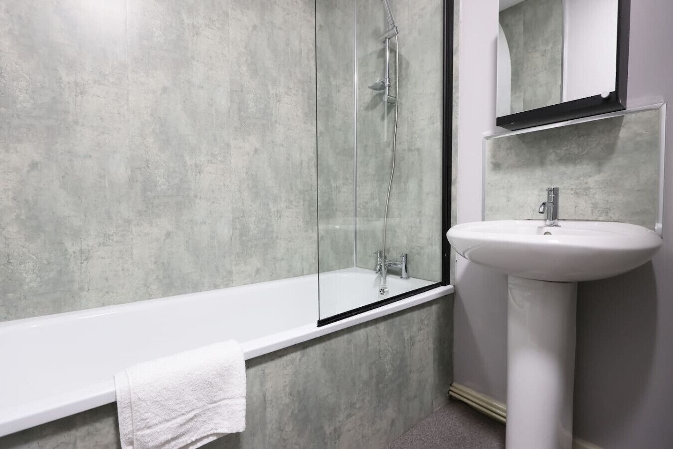 A modern bathroom with a glass-enclosed shower, a white sink, and a large mirror.