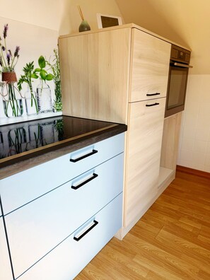 Eine Küche mit Holzschrank, schwarzer Arbeitsplatte und kleinem Backofen.