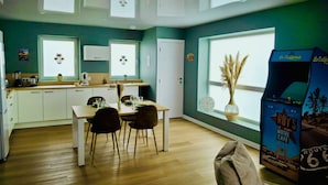 Una cocina moderna con armarios blancos, una mesa de comedor con sillas y un amplio ventanal con vistas a palmeras.