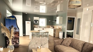 Una sala de estar moderna con un sofá, una mesa de comedor y una cocina al fondo.