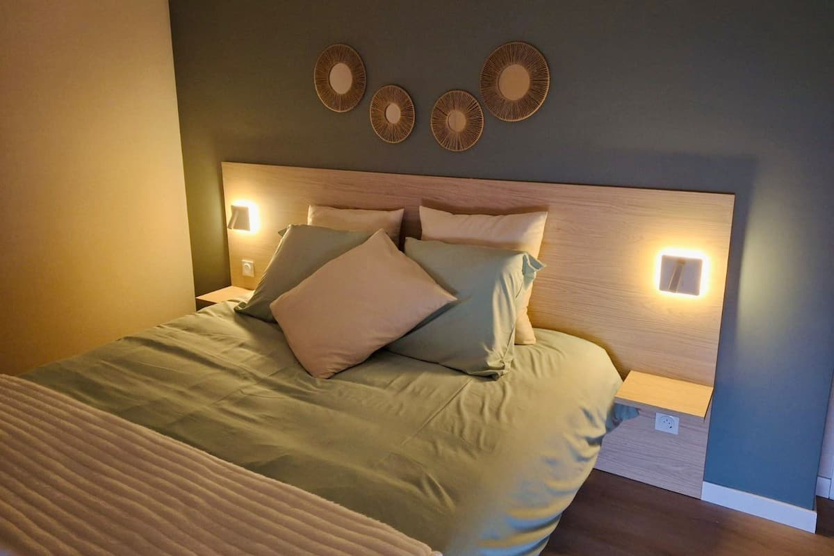 A neatly made bed with a wooden headboard, two wall-mounted light fixtures, and three circular wall decorations.