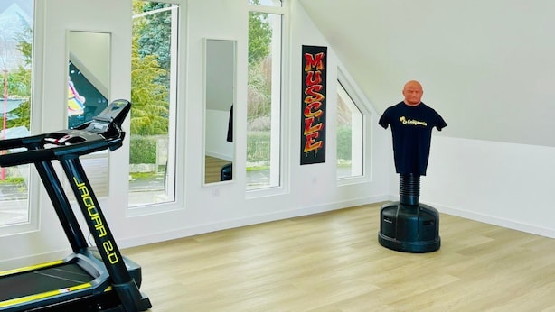 Quarto moderno com esteira, manequim e grandes janelas.