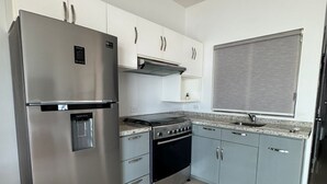 Eine Küche mit einem Edelstahl-Kühlschrank, einem Einbauofen und einer Mikrowelle.
