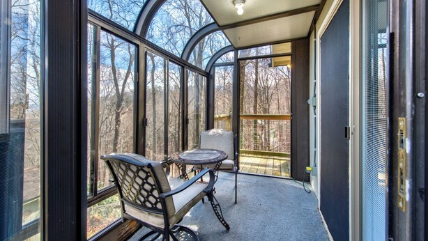A conservatory with a glass ceiling, a table, and a chair. - *Amazing 3BD w/ Hot Tub | Fire Pit + Pool Access* (Gatlinburg)
