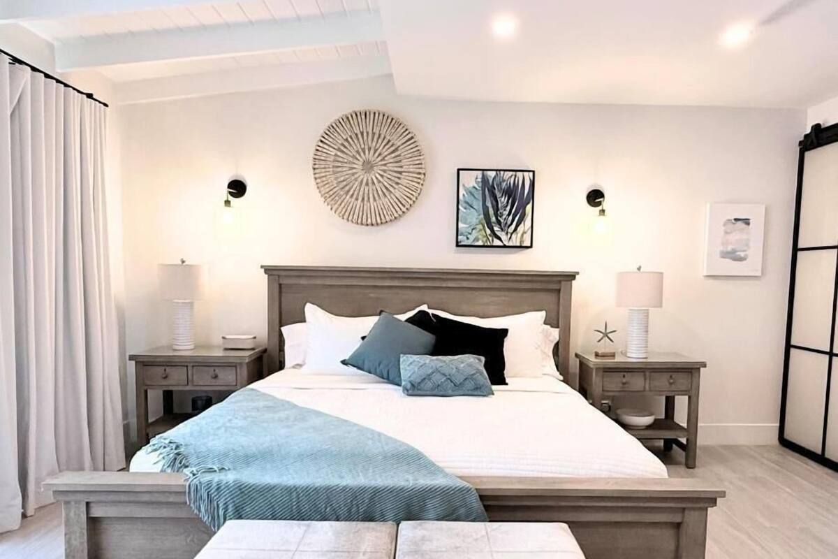 A modern bedroom with a large bed, bedside tables, a bench, and artwork on the walls.