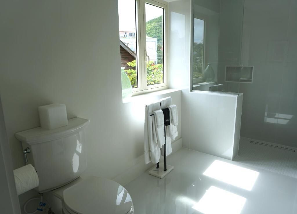 A modern bathroom with a toilet, a towel rack, and a window.