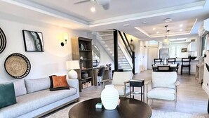 A modern living room with a sofa, coffee table, and a staircase leading to a dining area.