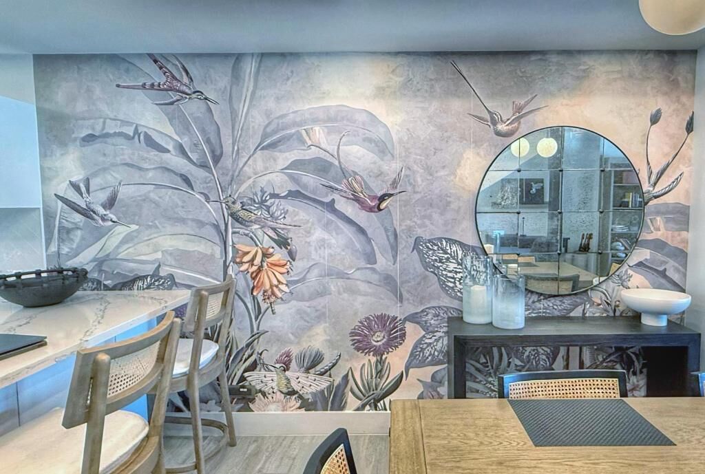 A dining area with a mural, round mirror, and modern furniture.