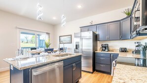 A modern kitchen with a central island, stainless steel appliances, and dark cabinetry. - Modern 3BD Home Near TOWN! Hot Tub + Games + VIEWS (Sevierville)