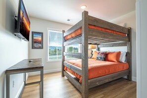 A bunk bed with a TV mounted on the wall, a desk, and a window with blinds. - Modern 3BD Home Near TOWN! Hot Tub + Games + VIEWS (Sevierville)