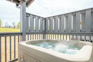 A hot tub in an outdoor setting with a wooden deck and a view of the landscape. - Modern 3BD Home Near TOWN! Hot Tub + Games + VIEWS (Sevierville)