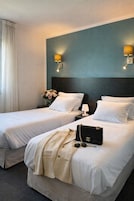 A hotel room with two beds, a nightstand, a lamp, and a decorative vase with flowers.