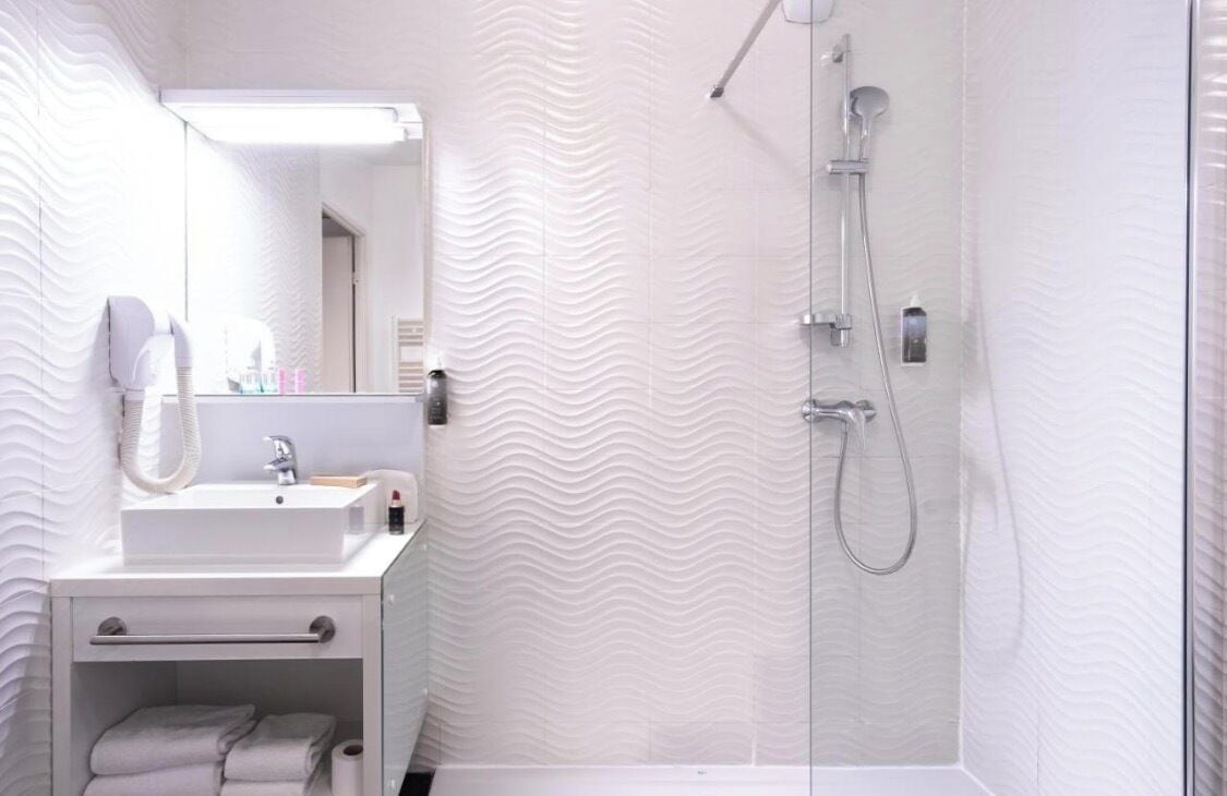 Une salle de bain moderne avec un lavabo blanc, un miroir et une douche.